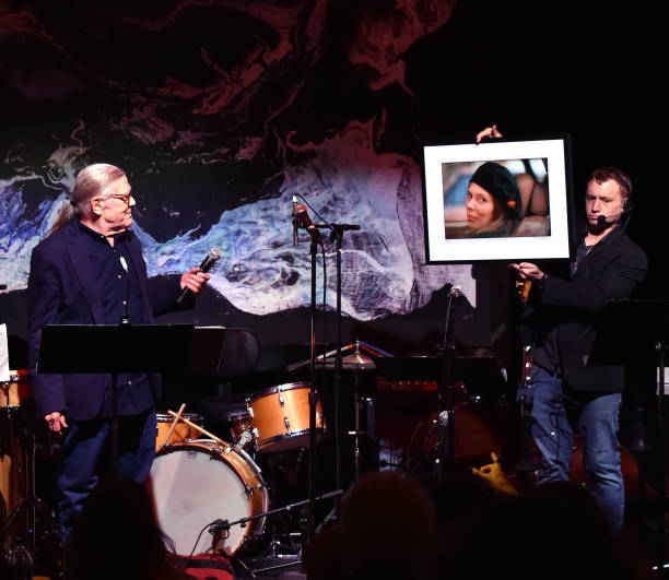 Henry Diltz auctioning off some of his photographs signed by Joni Mitchell. Photo by Lester Cohen [NYCRobert]