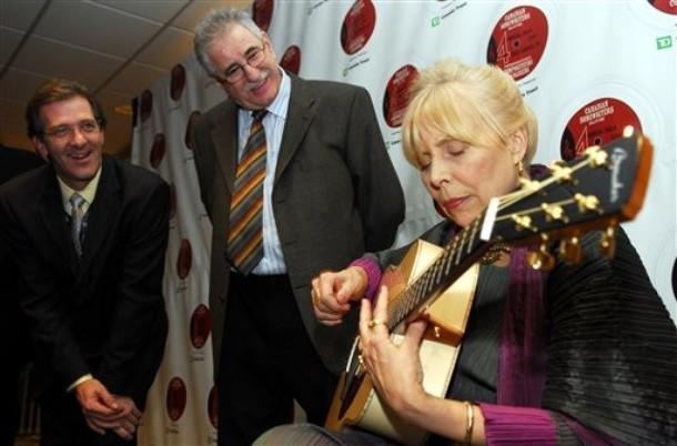 Joni plays a guitar presented to her by guitar makers Robin, left, and Claude Boucher.